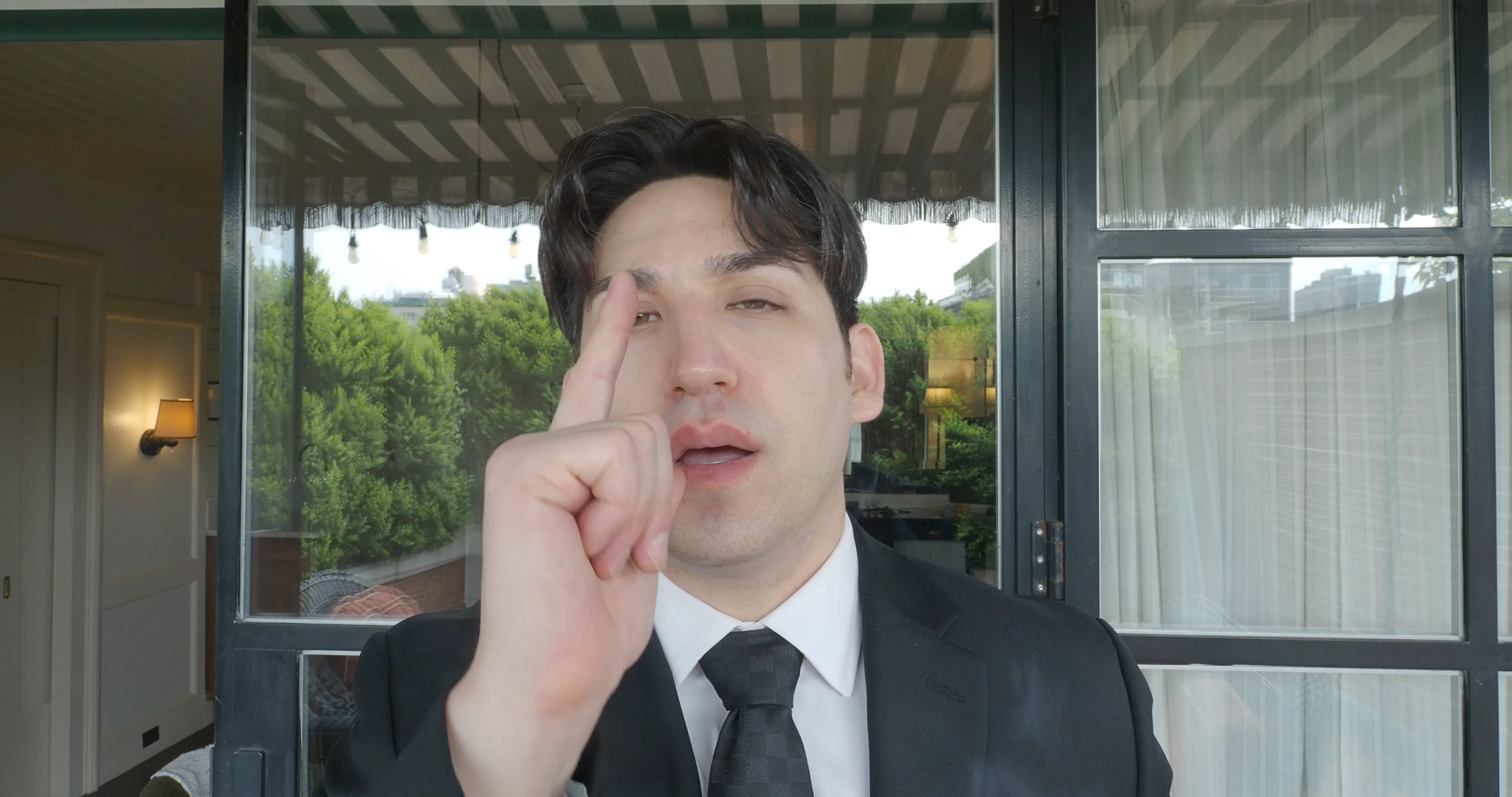 Ian Bloom as The Gangster in Big Time making a finger-gun gesture in the hotel room