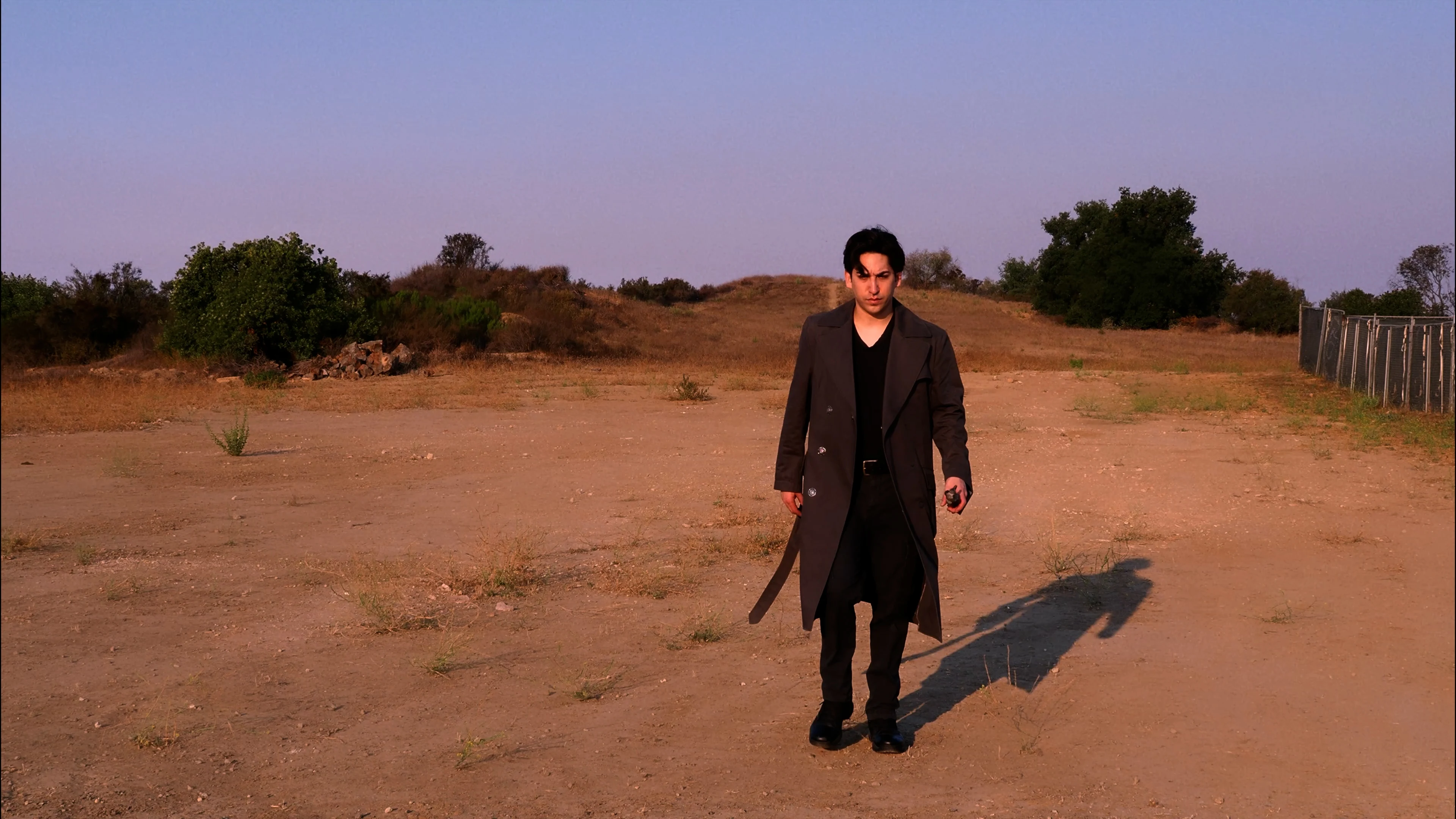Ian Bloom in King standing in the desert in a trench coat with a severe expression