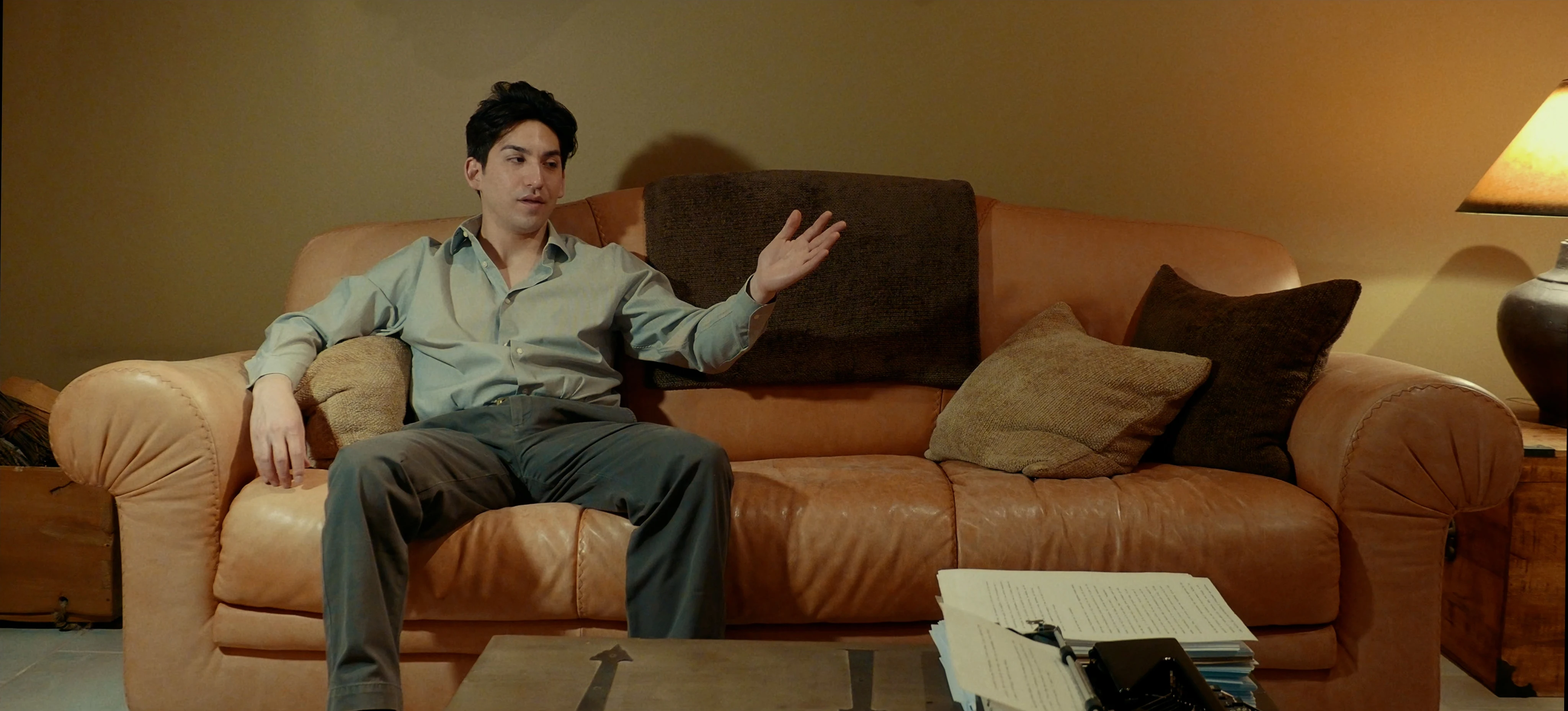 Ian Bloom as The Star in Star Vehicle seated indoors in a formal cinematic frame