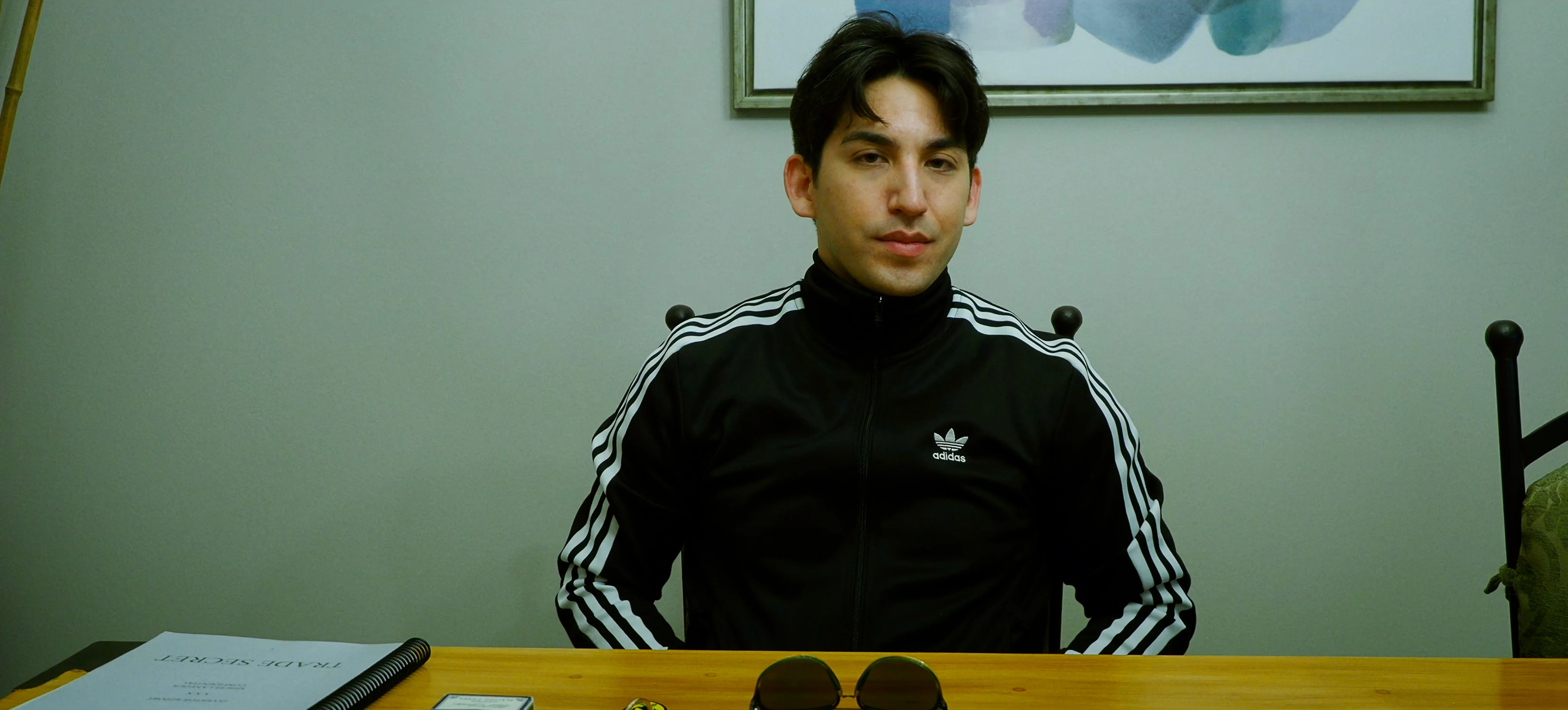 Ian Bloom as The Star in Star Vehicle seated at a table in a dark interior