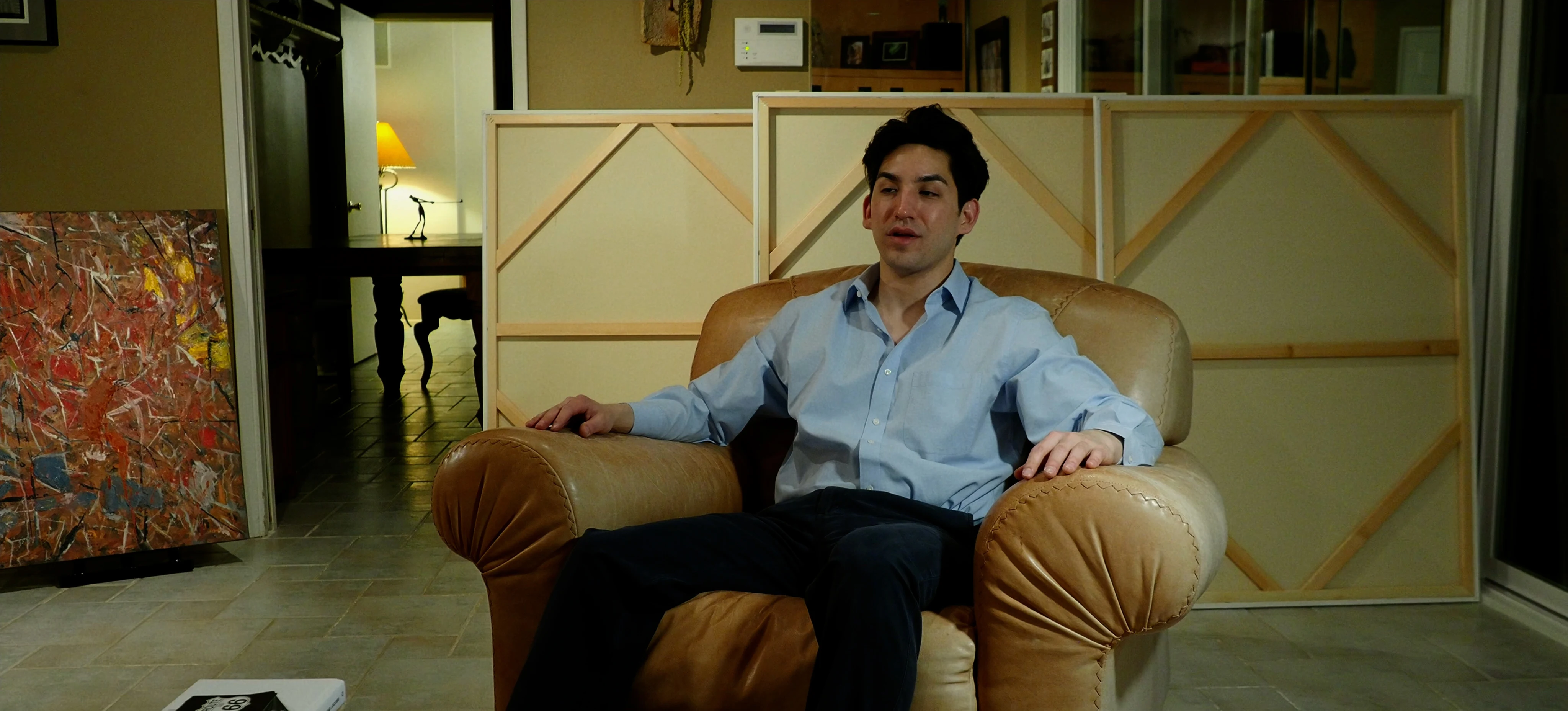 Ian Bloom as The Suit in Star Vehicle seated in a black suit during an interior scene